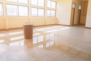 water leak drop interior office building in red bucket from Ceiling and flow on terrazzo floor