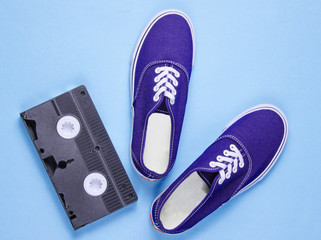 Wall Mural - Retro sneakers, video cassette on blue background. Pop culture,80s, top view