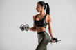© nikolas_jkd - Fitness woman doing exercise for biceps on gray background. Muscular woman workout with dumbbells