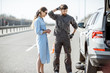 © rh2010 - Road assistance worker in uniform with young woman standing near the broken car on the highway