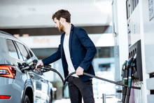 Businessman Refueling His Luxury Car Holding Filling Gun At The Gas Station