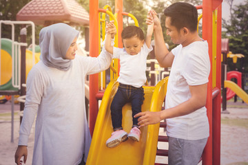 Wall Mural - Parents guide their daughter to play with a slide