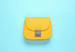 Yellow leather mini bag on blue background. Minimalism fashion concept. Top view