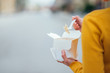 © bnenin - Unrecognizable woman with food to go in the city, close-up, copy space.