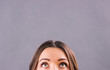 © Artem - Closeup beautiful young woman looking up on blank copy space isolated on gray background. Attractive funny girl staring above her head. Half face of adorable woman thinking about solution. Empty space