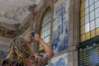 A tourist woman takes a photo with her mobile phone from the historical interior of the Sao Bento train station, in the city of Porto, Portugal