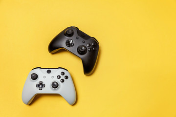 White and black two joystick gamepad, game console on yellow colourful trendy modern fashion pin-up background. Computer gaming competition videogame control confrontation concept. Cyberspace symbol