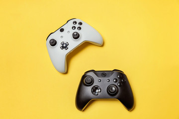 White and black two joystick gamepad, game console on yellow colourful trendy modern fashion pin-up background. Computer gaming competition videogame control confrontation concept. Cyberspace symbol