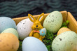 Easter bunny with colorful easter eggs in basket and grass