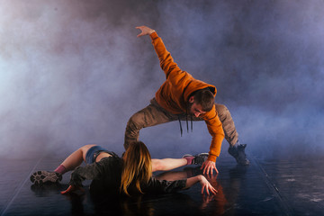 The beautiful female dancer is laying on the floor while her male partner performs an exotics unique modern art moves over her.