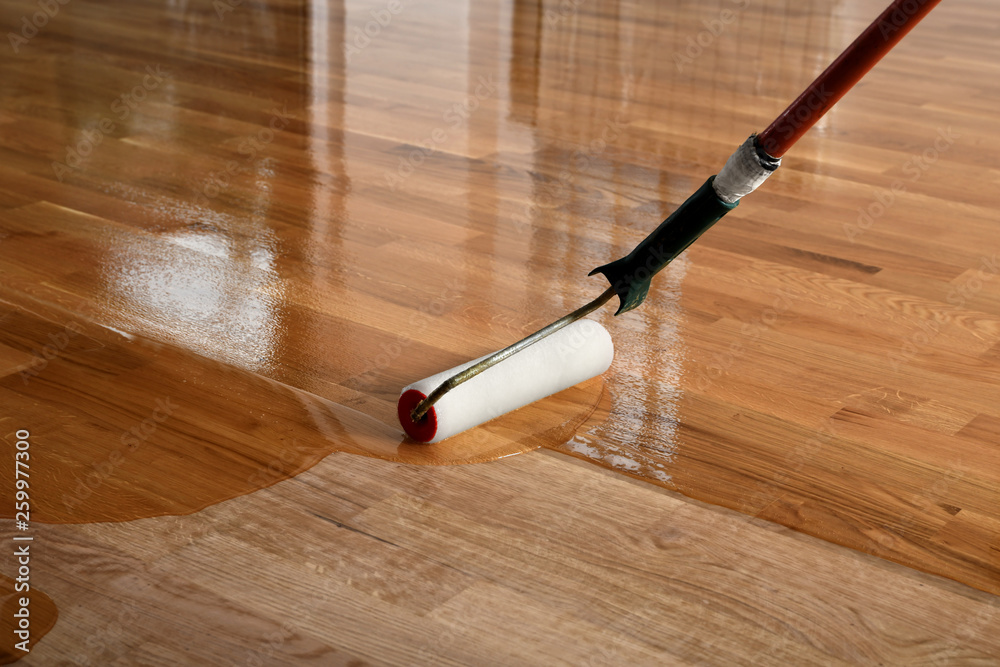 Lacquering wood floors. Worker uses a roller to coating floors. - obrazy, fototapety, plakaty 