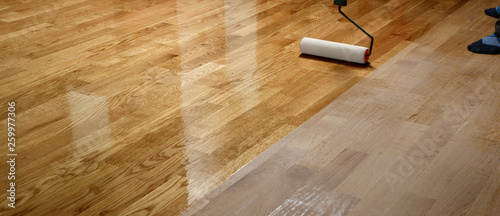 Fotomural Lacquering wood floors. Worker uses a roller to coating floors.