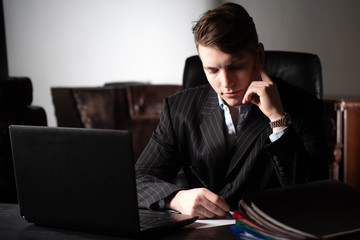 Poster - young businessman at work. man at the computer. a man writes at his desk. young entrepreneurs. busin
