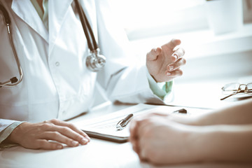 Doctor and  female patient sitting at the desk and talking  in clinic near window. Medicine and health care concept. Green is main color