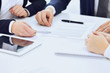 © rogerphoto - Group of business people and lawyers discussing contract papers sitting at the table, close-up. Successful teamwork, cooperation and agreement concepts