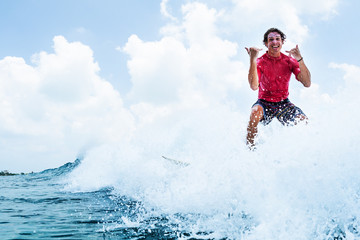 Wall Mural - Happy surfer rides the wave and shows the Shaka sign