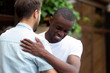 © fizkes - Happy two multiracial male best friends greeting embracing at meeting