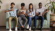 © fizkes - Multicultural people using smartphones ignoring each other sitting on sofa