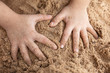 Leinwandbild Motiv Children's hands playing sand at beach