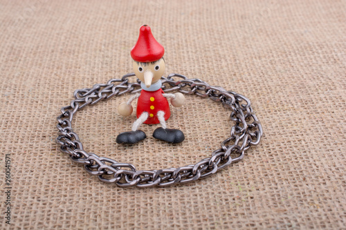 Chain around wooden Pinocchio doll sitting on canvas