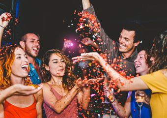 Wall Mural - Happy friends doing party throwing confetti in the club - Millennial young people having fun celebrating in the nightclub - Nightlife, entertainment and youth festive holidays concept