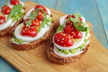 Wall Mural - homemade sandwiches with avocado boiling egg cream cheese cherry tomatoes sesame seeds on cutting board