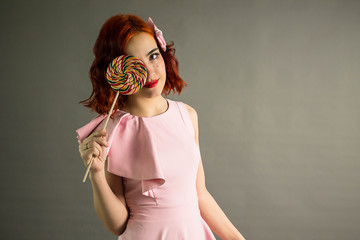 Portrait of a girl with a Lollipop on a gray background. Puppet image.