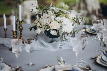 banquet table is decorated with plates, cutlery, glasses, candles and flower arrangements