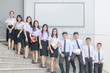 © kwanchaichaiudom - students stand and smile on stairs with white billboard