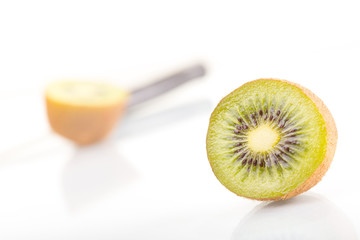 Green fresh kiwi fruit cut into half and knife on a white background