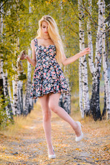 Wall Mural - An attractive girl with long hair in a short dress and heels with a gas mask in her hands walks in the Park.