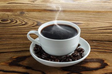 Chocolate with hot steam and coffee beans on wooden table