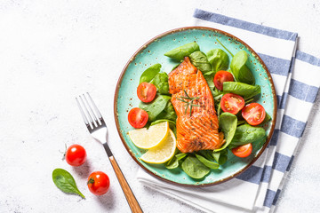 Baked salmon fish fillet with fresh salad top view on white.