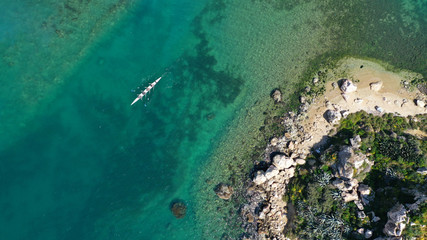 Wall Mural - Aerial drone bird's eye view of sport canoe operated by team of young women in tropical caribbean exotic island with emerald and sapphire clear sea