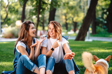 Wall Mural - Candid friends seated at the park talking to each other.