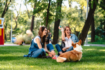 two female friend in the park play with little dog