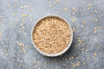 Wall Mural - Rolled oats or oat flakes in bowl, table top view. Concept of healthy eating, dieting, vegan or vegetarian diet