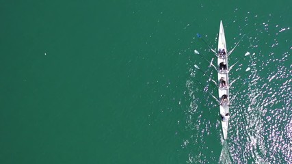 Wall Mural - Aerial drone bird's eye top view video of sport canoe operated by team of young men and women in open ocean sea