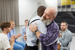 © Seventyfour - Side view  portrait of senior man hugging psychologist during therapy session in support group, copy space