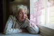 Portrait of old lady sitting at the table. Pensioner.