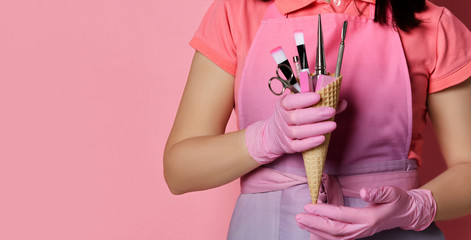 Wall Mural - Woman hands in pink medicine gloves hold waffle cone with brush, scissors, nail file with abrasive 