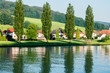 Poplar trees front a quaint village and cast a reflection in the Danube River