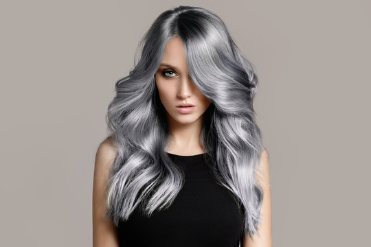 beautiful woman with long wavy coloring hair. flat gray background.