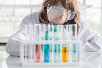 Wall Mural - a young asian woman scientist working in laboratory holding magnifying glass with test tubes and sol