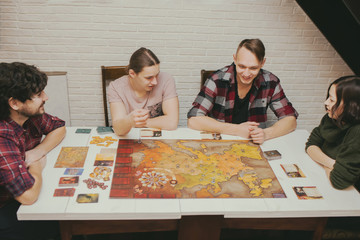 Group of friends sitting at the table. Young People having fun while playing board game.