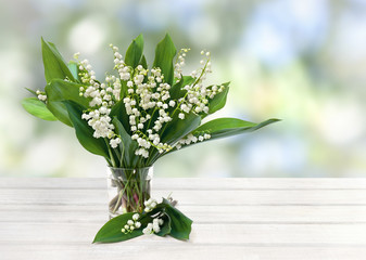 Wall Mural - bouquet of flowers and leaves lily of the valley ( convallaria majalis ) in small glass on white woo