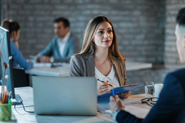 Wall Mural - Smiling businesswoman going through business reports with her colleague in the office.