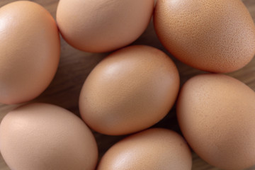 Brown raw eggs wooden background top view