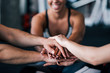 © bnenin - Close-up of sports team stacking hands while sitting in the gym.