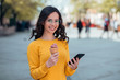 © bnenin - Portrait of a casual young woman eating ice cream and using phone in the city street.